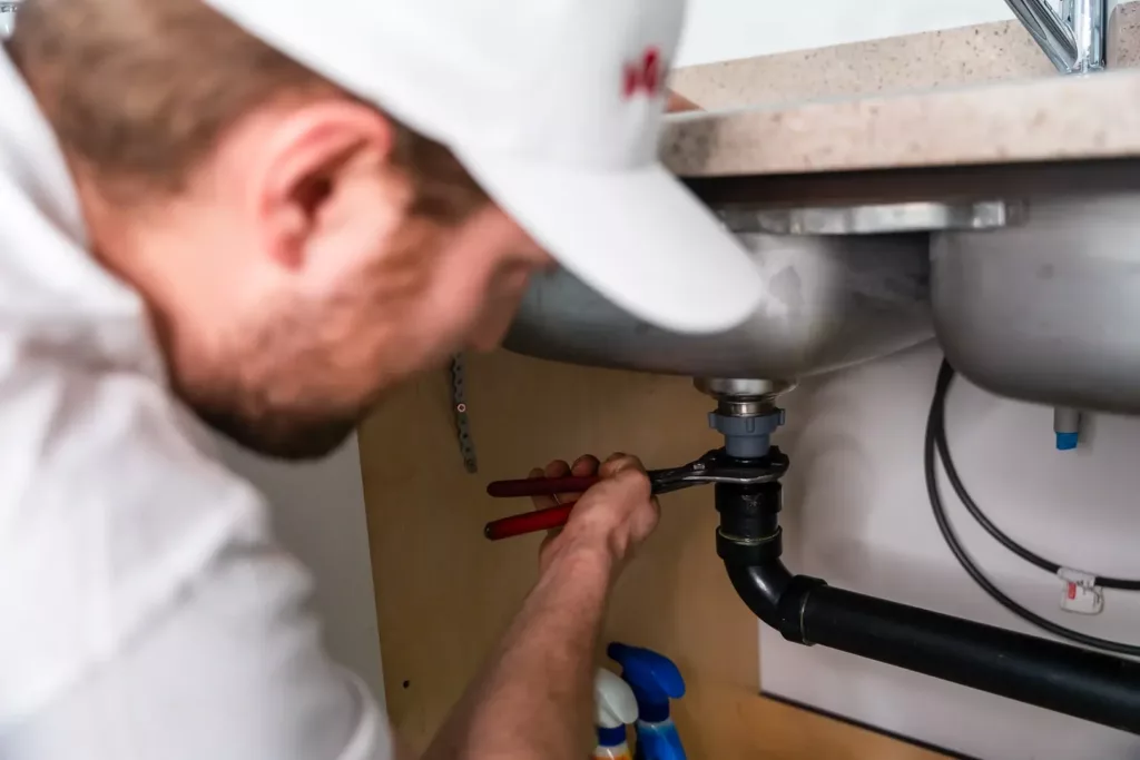 A plumber is doing plumbing installation in a residential kitchen.